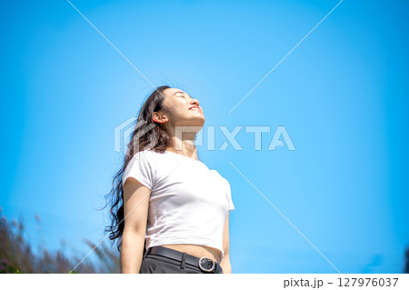 青空のもとでリラックスする若い女性 127976037