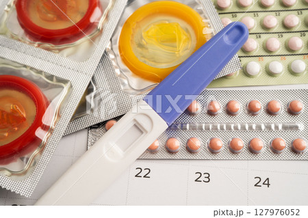 Pregnancy test and birth control pills on calendar, contraception health and medicine. 127976052