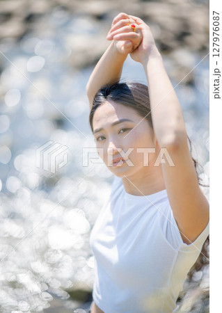 川沿いでリラックスする若い女性 127976087