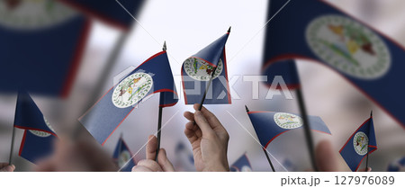 Belize flags in their hands on a blurred urban background 127976089