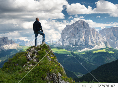 Hiker standing on a peak, breathtaking mountain range 127976107