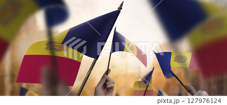 Andorra flags in their hands on a blurred urban background Andorra flags in their hands on a blurred urban background 127976124