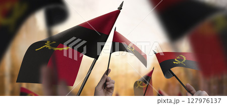 Angola flags in their hands on a blurred urban background 127976137