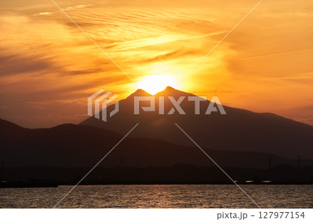 霞ヶ浦から望む夕暮れ時の筑波山と山頂に位置する太陽 127977154