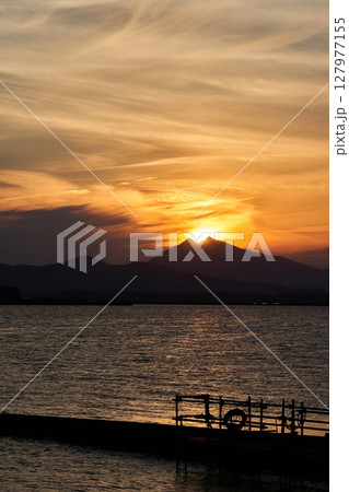 霞ヶ浦から望む夕暮れ時の筑波山と山頂に位置する太陽 127977155