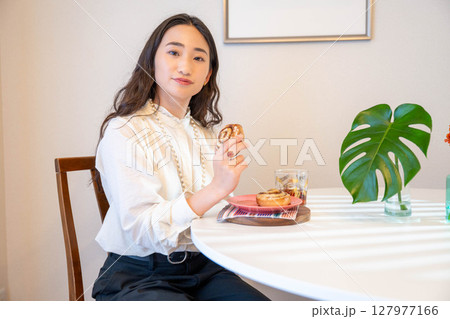 パンを楽しそうに食べる若い女性 パンを楽しそうに食べる若い女性 127977166