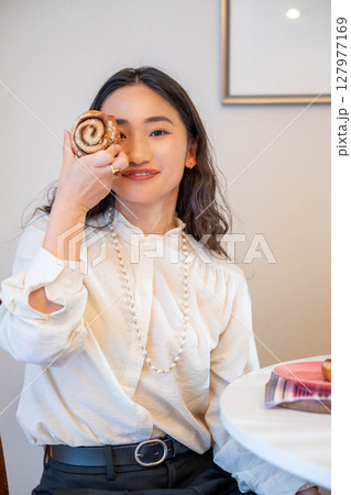 パンを楽しそうに食べる若い女性 127977169