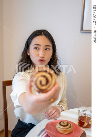 パンを楽しそうに食べる若い女性 パンを楽しそうに食べる若い女性 127977188
