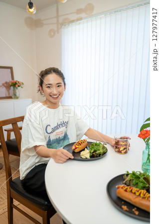 室内でカジュアルな格好をしながらご飯を食べる若い女性 室内でカジュアルな格好をしながらご飯を食べる若い女性 127977417