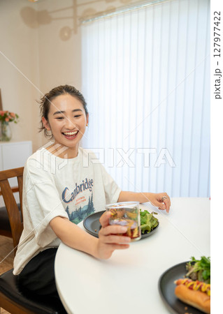 室内でカジュアルな格好をしながらご飯を食べる若い女性 室内でカジュアルな格好をしながらご飯を食べる若い女性 127977422