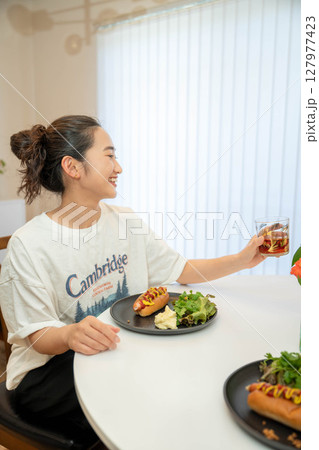 室内でカジュアルな格好をしながらご飯を食べる若い女性 室内でカジュアルな格好をしながらご飯を食べる若い女性 127977423