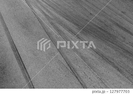Abstract asphalt street road background with black tire marks on race track, Texture and background car automobile and automotive skid tire marks. Abstract asphalt street road background with black tire marks on race track, Texture and background car automobile and automotive skid tire marks. 127977703