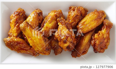 Crispy fried chicken wings coated in a sweet and tangy sauce. These mouthwatering appetizers are perfect for sharing! 127977906