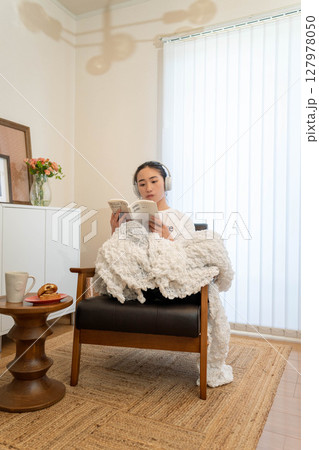 毛布をかぶってリラックスしている若い女性 毛布をかぶってリラックスしている若い女性 127978050