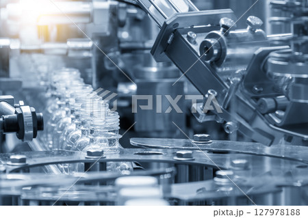 The empty drinking water bottles on the conveyor belt for filling process in the light blue scene. The empty drinking water bottles on the conveyor belt for filling process in the light blue scene. 127978188