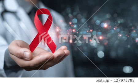 Symbol of hope and awareness in healthcare. Doctor's hand holds a red ribbon, promoting global support for health initiatives and disease awareness. Symbol of hope and awareness in healthcare. Doctor's hand holds a red ribbon, promoting global support for health initiatives and disease awareness. 127978795