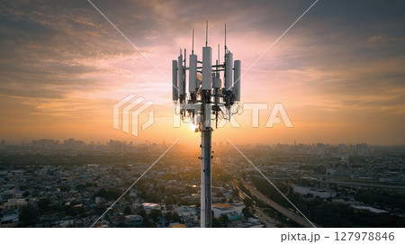 Cell tower rises above cityscape at sunset, connecting communication networks and symbolizing modern infrastructure. Cell tower rises above cityscape at sunset, connecting communication networks and symbolizing modern infrastructure. 127978846
