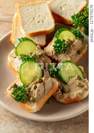 Open sandwiches with pate, cucumber, capers, and parsley. Open sandwiches with pate, cucumber, capers, and parsley. 127979276