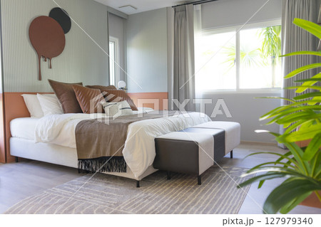 Comfortable bed with brown stylish linens and pillow with painting on wall. Interior design. Comfortable bed with brown stylish linens and pillow with painting on wall. Interior design. 127979340