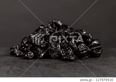 piled on a board made of stone dried plum close up, dried fruits on black slate piled on a board made of stone dried plum close up, dried fruits on black slate 127979416