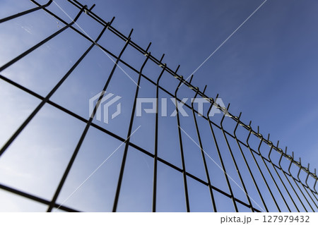 metal lattice fence against a sky background, a small thin fence dividing the territory metal lattice fence against a sky background, a small thin fence dividing the territory 127979432