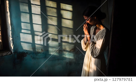 woman praying in dimly lit room 127979781