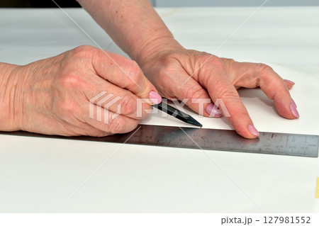 Creating a pattern by a seamstress using a ruler and pencil. Creating a pattern by a seamstress using a ruler and pencil. 127981552