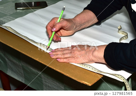 Creating a pattern by a seamstress using a ruler and pencil. Creating a pattern by a seamstress using a ruler and pencil. 127981565