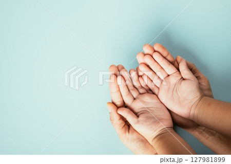 Family hands stack in close-up top view isolated background. Parents and child hold empty space together expressing support on Family and Parents Day. 127981899