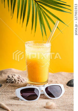 Colourful orange cocktail in a tall glass on a sand Colourful orange cocktail in a tall glass on a sand 127981913