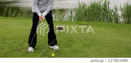 Female Golfer Preparing to Swing at a Tournament Near a Pond Female Golfer Preparing to Swing at a Tournament Near a Pond 127981996