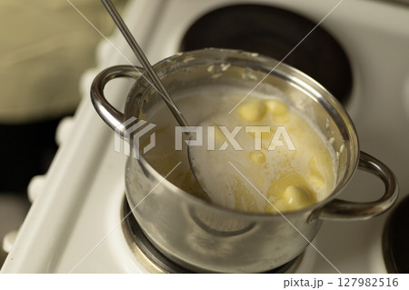 stirring sweet cream ghee with a metal spoon with holes stirring sweet cream ghee with a metal spoon with holes 127982516