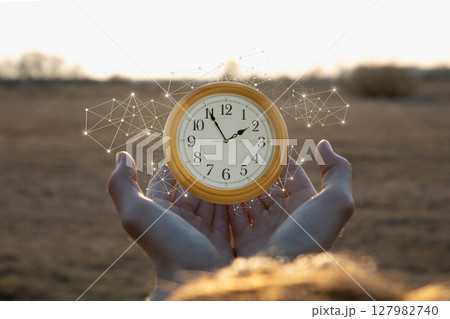 Holding time in hands with a glowing clock display 127982740