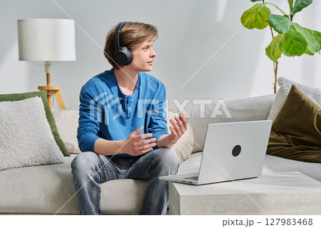 Teenage boy with headphones using laptop for video conference, online meeting 127983468