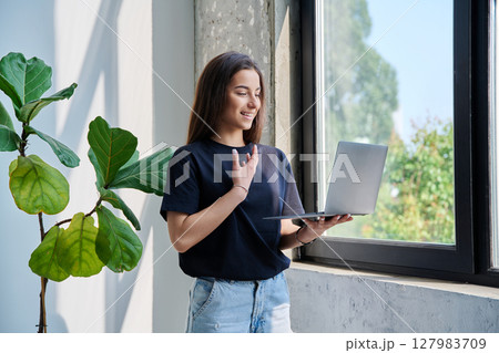 Young teenage girl using laptop for video chat conference standing at home 127983709