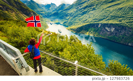 Tourist over Geirangerfjord with norwegian flag Tourist over Geirangerfjord with norwegian flag 127983726