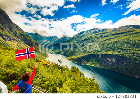 Tourist over Geirangerfjord with norwegian flag 127983731