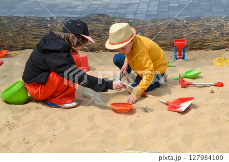 Good leisure for a child. Teaching a child through play. A handsome boy 3 oldl in a yellow jacket excavates the remains of dinosaurs. High quality photo. Good leisure for a child. Teaching a child through play. A handsome boy 3 oldl in a yellow jacket excavates the remains of dinosaurs. High quality photo. 127984100