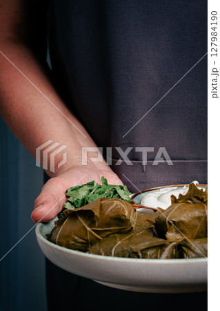 A man holds a plate in his hands, a dolma with sauce and lemon. A man holds a plate in his hands, a dolma with sauce and lemon. 127984190