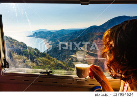 Woman in rv enjoy coast view, drinking coffee Woman in rv enjoy coast view, drinking coffee 127984624