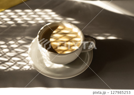 cup of coffee with netting shadows from the sun's rays cup of coffee with netting shadows from the sun's rays 127985253