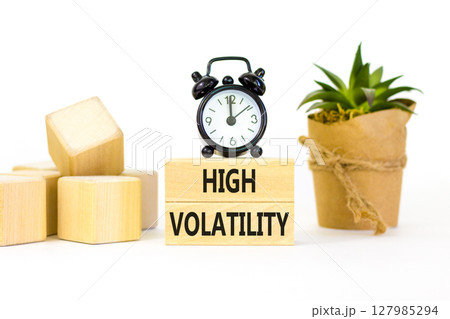 High volatility symbol. Concept words High volatility on beautiful wooden blocks. Beautiful white table white background. Black alarm clock. Business high volatility concept. Copy space. 127985294