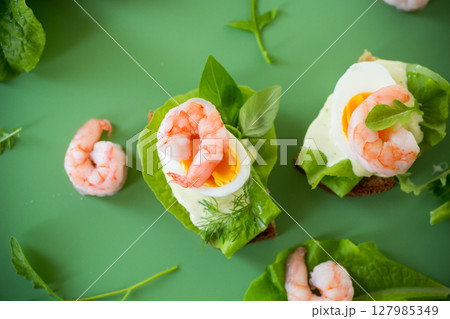Appetizing breakfast with shrimp, egg and greens on top 127985349
