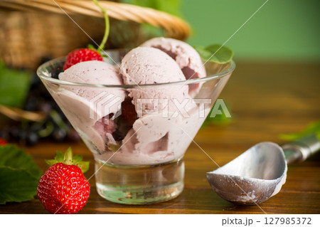 Blackcurrant ice cream with strawberries on green background 127985372