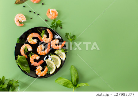 Appetizing boiled shrimps with lemon isolated on green background 127985377