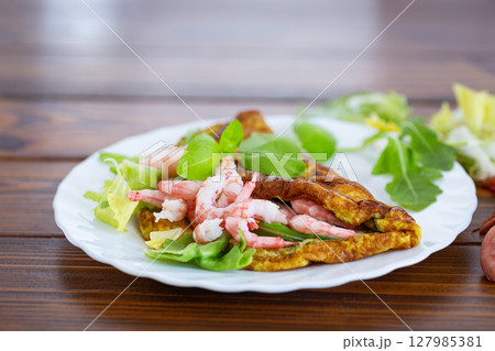 Delicious omelette with shrimps and fresh greens on top Delicious omelette with shrimps and fresh greens on top 127985381