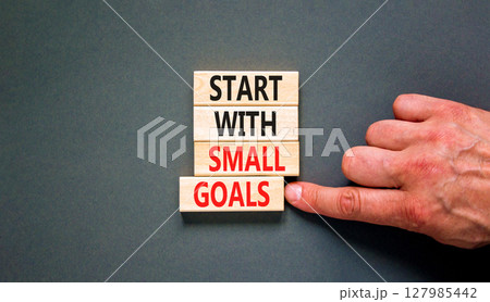 Start with small goals symbol. Concept words phrase Start with small goals on beautiful wooden blocks. Beautiful grey background. Businessman's hand. Business Start with small goals concept Copy space 127985442