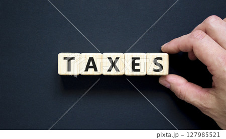 Taxes symbol. Concept word Taxes on beautiful wooden blocks. Beautiful black table black background. Businessman hand. Business lifestyle taxes concept. Copy space. 127985521