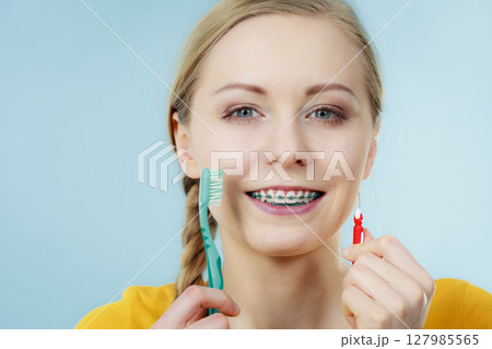 Girl with teeth braces using interdental and traditional brush Girl with teeth braces using interdental and traditional brush 127985565