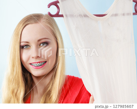 Happy smiling woman next to short white dress Happy smiling woman next to short white dress 127985607